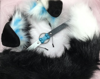May include: A cosplay set featuring a pair of black and white faux fur ears with blue accents, a matching black and white tail, and a collar with a blue bone-shaped charm. The set is designed to resemble a canine.