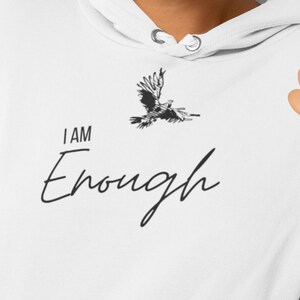 May include: White hoodie featuring a black eagle graphic and the text "I AM Enough" in a cursive font.