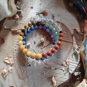 May include: A rainbow chakra bracelet made with natural stones, including clear quartz, tiger's eye, lapis lazuli, amethyst, green aventurine, red jasper, and carnelian.