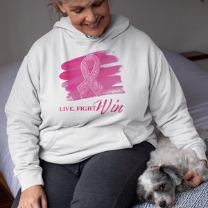May include: White hoodie with a pink watercolor design of a ribbon with the text "LIVE. FIGHT. Win" printed on the front.