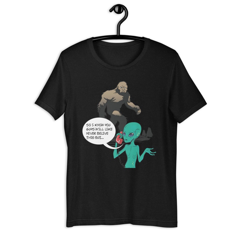 May include: Black t-shirt with a graphic of a green alien on the phone with a large, brown Bigfoot. The alien says, "So I know you guys will like never believe this but..."