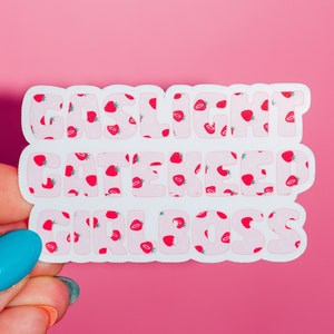 May include: White sticker with pink letters that say "Gaslight Gatekeep Girlboss" with a strawberry pattern.