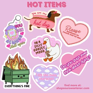 May include: A set of 9 colorful stickers with various designs and phrases. The stickers include a hot dog, a goose, a dumpster fire, a heart with the text "Please hesitate to reach out to me", a heart with the text "I am the main character", a heart with the text "Do you guys ever think about dying?", and a game console with the text "You can always start again".