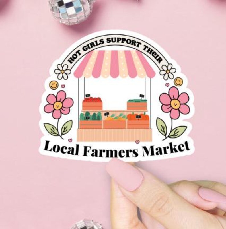 Pu&ograve; includere: Un adesivo rosa e bianco con un'illustrazione di un chiosco di un mercato contadino con il testo "Hot Girls Support Their Local Farmers Market".