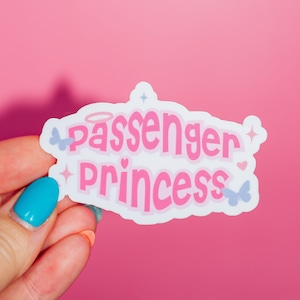 May include: White sticker with pink text that reads "Passenger Princess" with a halo above the word "Passenger" and small butterfly and star graphics.