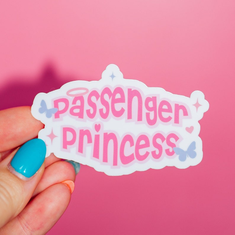 May include: White sticker with pink text that reads "Passenger Princess" with a halo above the word "Passenger" and small butterfly and star graphics.