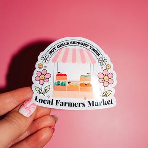 Pu&ograve; includere: Un adesivo bianco con un tendone a strisce rosa e bianche sopra un piccolo stand di mercato con prodotti. L'adesivo dice "Hot Girls Support Their Local Farmers Market" in testo nero.