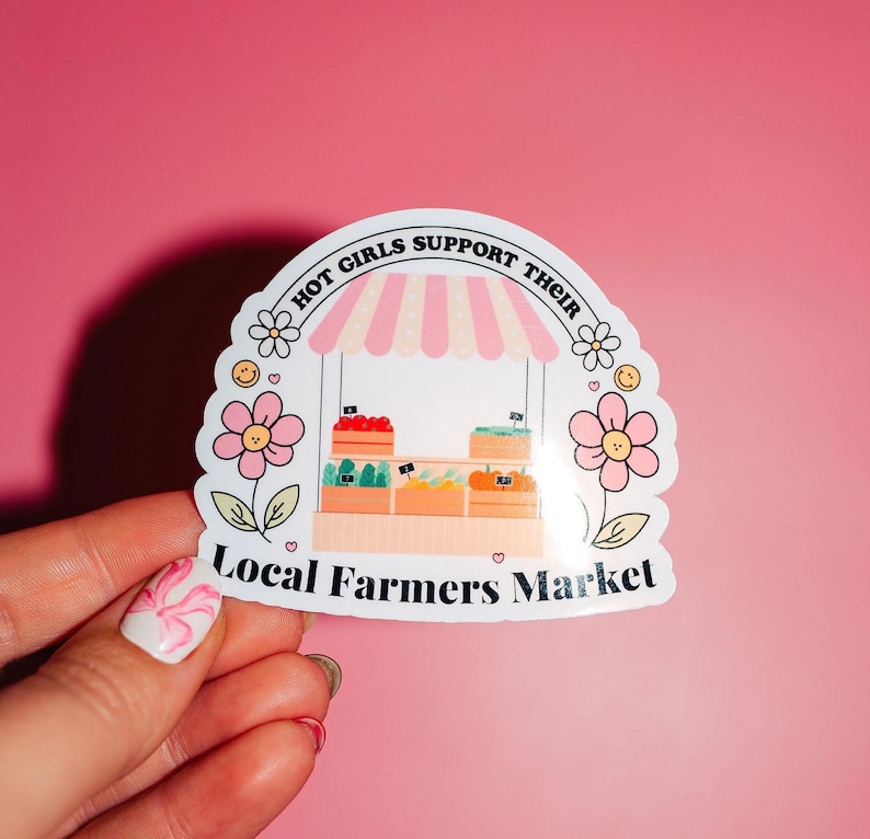 Pu&ograve; includere: Un adesivo bianco con un tendone a strisce rosa e bianche sopra un piccolo stand di mercato con prodotti. L'adesivo dice "Hot Girls Support Their Local Farmers Market" in testo nero.