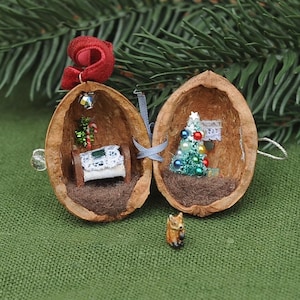 May include: A miniature diorama inside a split walnut shell featuring a tiny bed with a white lace coverlet and a small Christmas tree decorated with colorful ornaments. A small fox figurine stands in front of the shell, which is topped with a red ribbon.