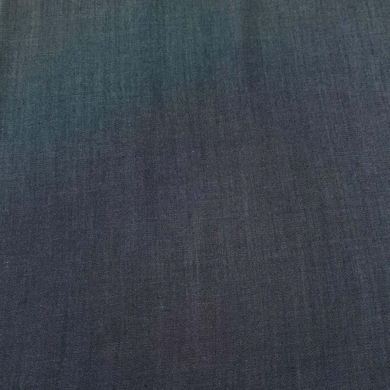 Puede incluir: Primer plano de una tela azul oscuro. La tela tiene una textura sutil y un efecto degradado, pasando de un azul m&aacute;s claro en la parte superior a un tono m&aacute;s oscuro en la parte inferior. El material parece ser un tejido.