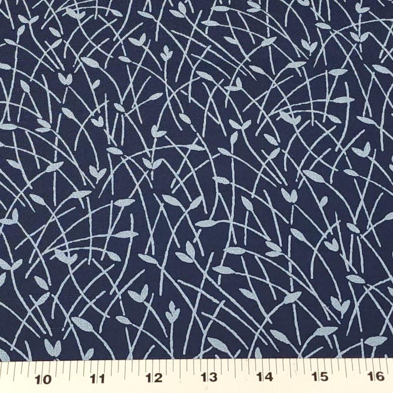 May include: Dark navy blue fabric with a repeating pattern of light blue, stylized leaves and curved lines. The design creates a sense of movement and organic texture. The fabric is measured in inches.