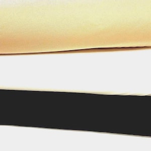 May include: Three stacked layers of fabric in distinct colors. The top layer is a soft, light beige or cream hue. The middle layer is a solid, bright white. The bottom layer is a deep, solid black. Each piece of fabric is smooth and flat.