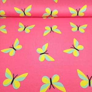 May include: Bright pink fabric with a repeating pattern of colorful butterflies. Each butterfly has yellow and light blue wings with black bodies. The fabric is folded over at the top, showing the pattern's continuity.
