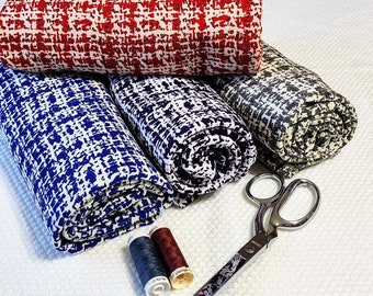May include: Three rolls of fabric with a geometric pattern in red, blue, and gray. The fabric is rolled up and placed on a white surface. There are two spools of thread in blue and red on the surface.