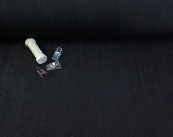 May include: A dark navy blue fabric roll with a textured surface. A white spool of thread and three plastic sewing clips in blue and purple are scattered on the fabric.