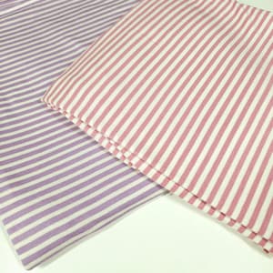 May include: Two fabric pieces with a striped pattern. One is lavender with white stripes, and the other is pink with white stripes. The stripes run vertically across the fabric, creating a classic design. The fabric appears to be cotton or a similar material.