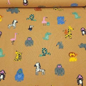 May include: Tan fabric with a repeating pattern of colorful cartoon animals, including zebras, giraffes, elephants, and monkeys. The illustrations are in shades of blue, yellow, pink, and green. The fabric is suitable for children's apparel or nursery decor.