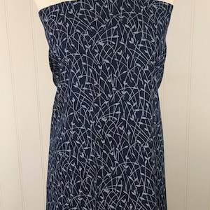 May include: A navy blue fabric draped over a mannequin. The fabric features a delicate, light blue pattern of curved lines and small leaf-like shapes. The fabric is likely used for clothing or home decor.