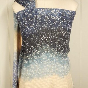 May include: A blue and white patterned fabric draped over a mannequin. The fabric has a gradient effect, changing from dark blue at the top to a light cream colour at the bottom. The pattern includes small white floral sprigs.