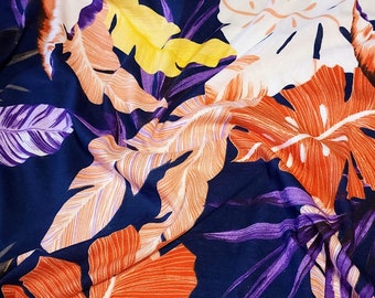 Tissu jersey de coton, joli imprimé tropical violet, corail et jaune sur bleu marine. Extensible dans les 2 sens. Pièce restante de 32 pouces.
