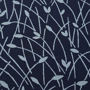May include: Close-up of a navy blue fabric with a repeating pattern of light blue, stylized plant stems and leaves. The design features thin, curved lines and oval and heart-shaped leaf forms, creating a textured, organic aesthetic.
