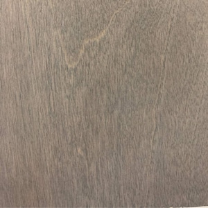 May include: Close-up of a wooden surface with a gray stain. The wood grain is visible, running diagonally across the frame. The surface has a smooth, matte finish, with subtle variations in color.
