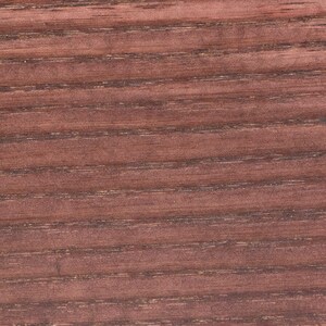 May include: Close-up of a reddish-brown wood grain pattern. The wood grain has a horizontal striped design with dark brown lines and a smooth, polished texture. The wood appears to be stained or treated.