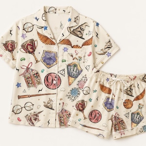 May include: A cream-colored short-sleeve button-down pajama shirt and matching shorts set featuring a repeating print of wizarding world icons including a sorting hat, golden snitch, wand, round glasses, and a bottle labeled Felix Felicis.