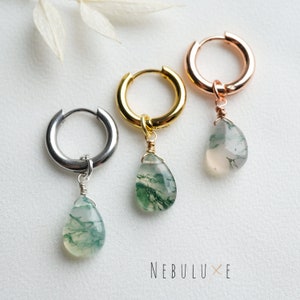 May include: Three hoop earrings with a teardrop-shaped green moss agate pendant hanging from each. The hoops are silver, gold, and rose gold.
