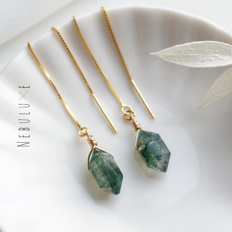 May include: A pair of gold chain earrings with green moss agate stones. The stones are faceted and have a natural, organic look.
