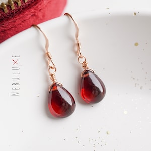Peut inclure: Une paire de boucles d'oreilles en or rose avec des pendentifs en forme de goutte de pierre précieuse rouge.