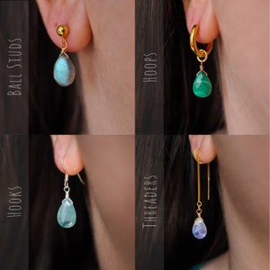 May include: Four different styles of earrings with gemstone drops. The styles are ball studs, hoops, hooks, and threaders. The gemstones are labradorite, malachite, aquamarine, and moonstone.