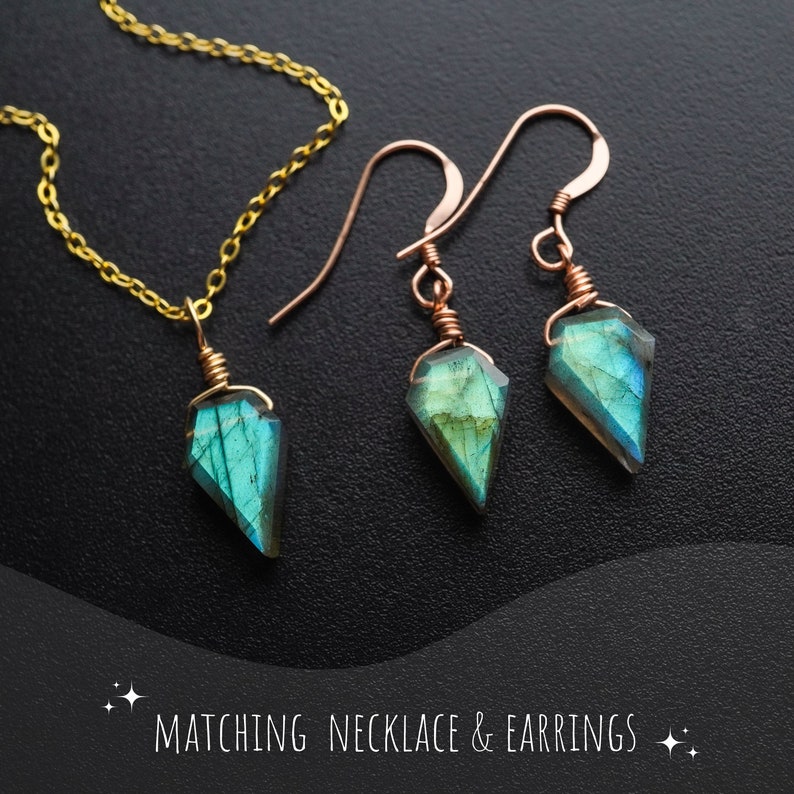 May include: A matching jewelry set featuring a necklace and earrings. The necklace has a gold chain with a pendant of a faceted, blue-green gemstone. The earrings have copper-colored hooks and matching gemstone pendants. The text "MATCHING NECKLACE & EARRINGS" is at the bottom.