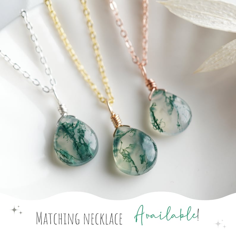 May include: Three delicate necklaces with moss agate pendants. The necklaces are available in silver, gold, and rose gold chains. The moss agate stones are a light green color with dark green veins.