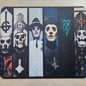 Könnte beinhalten: Eine schwarz-weiße Mauspad mit einer Collage von fünf maskierten Figuren in verschiedenen Posen. Die Figuren tragen schwarz-weiße Kleidung und haben eine gotische Ästhetik.