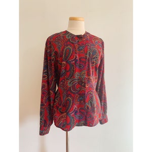 May include: A red paisley print long-sleeved blouse with a button-up front.