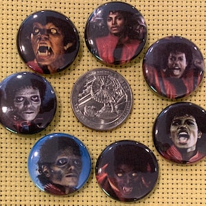 Puede incluir: Conjunto de ocho pines redondos con botón que presentan diferentes imágenes de Michael Jackson. Los pines son coloridos y presentan varias imágenes de Michael Jackson, incluyendo un hombre lobo, un zombi y un retrato más tradicional.