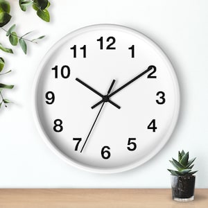 May include: A white analog clock with black hands and black numbers on a white background. The clock is set to 1:07.