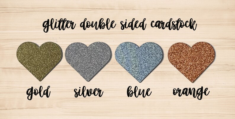 May include: Image of four glitter double-sided cardstock hearts in gold, silver, blue, and orange. The word "glitter double sided cardstock" is written above the hearts. Below each heart is the color name in a cursive font.