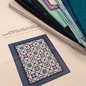 May include: A quilt kit for a January 2018 Block of the Month project featuring a quilt pattern with a blue, teal, and white color scheme. The kit includes fabric pieces and instructions for a 69 x 90 inch quilt. The kit is by Shelley Cavanna featuring Boundless Collage.