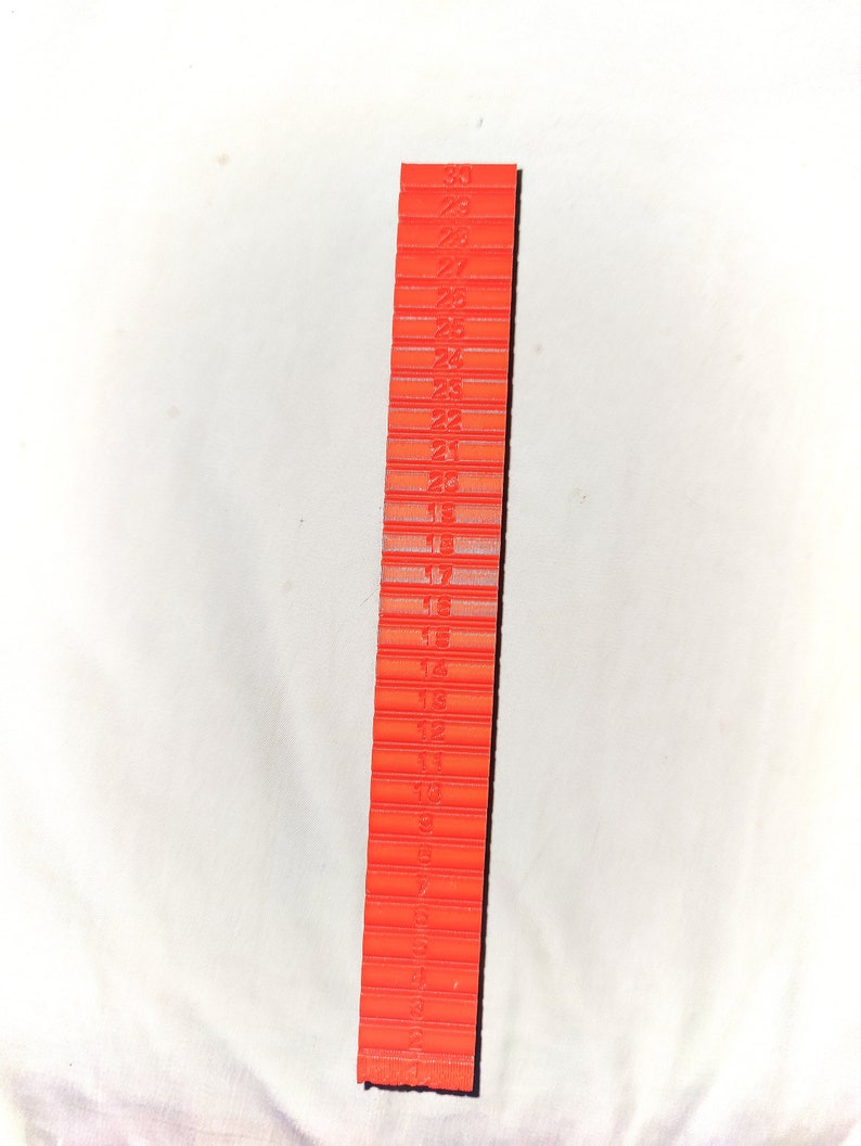 May include: A red plastic ruler with numbers 1 through 30 printed on it.