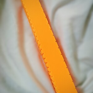 May include: A long, orange bar with a textured surface and multiple grooves running along its length.