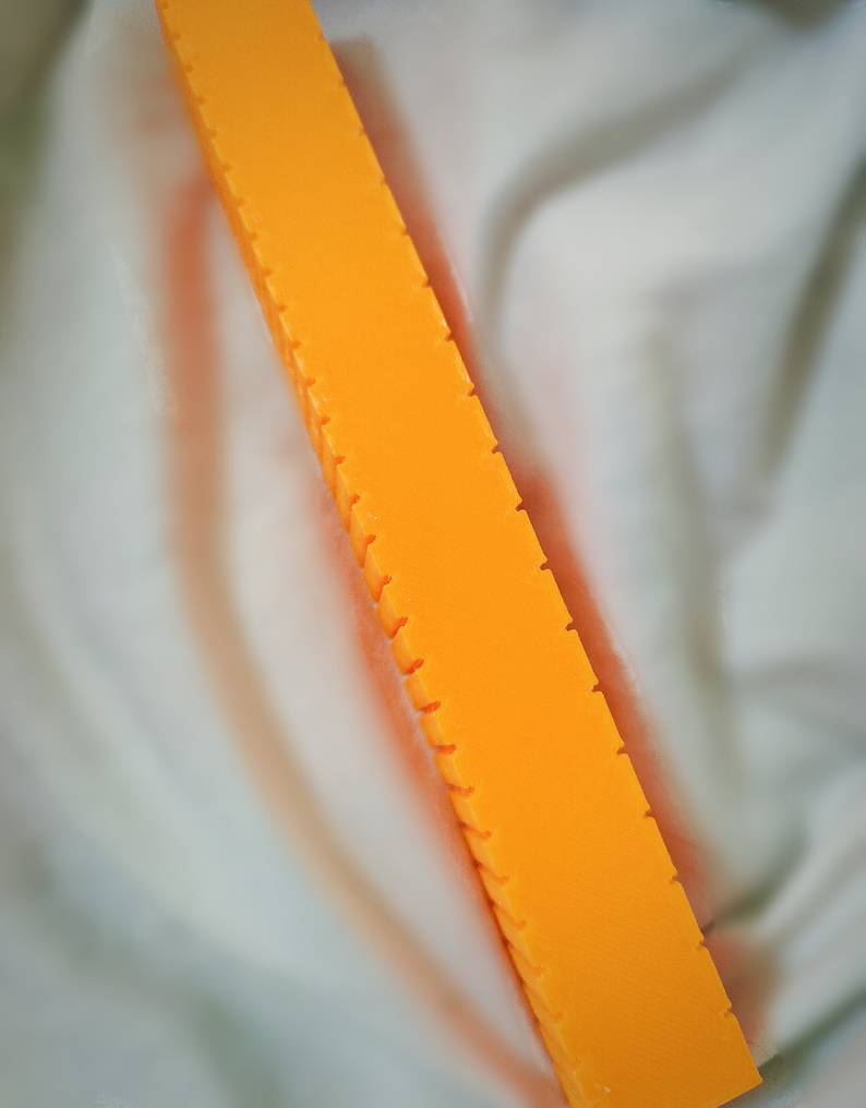 May include: A long, orange bar with a textured surface and multiple grooves running along its length.