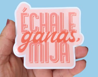 May include: Pink and orange sticker with the text "Échale ganas, mija" in a bold, stylized font.