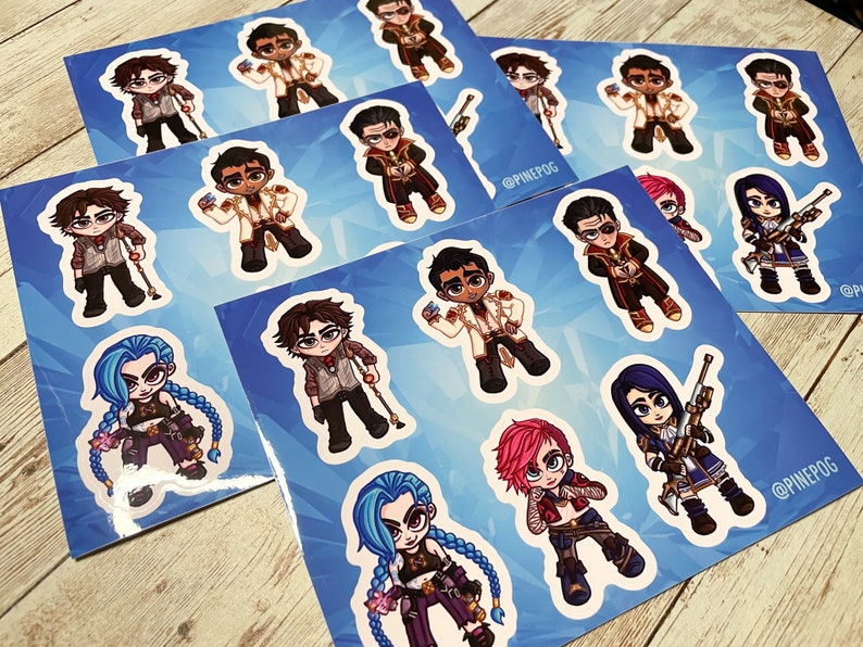 May include: A set of 10 colorful cartoon stickers featuring characters from the video game League of Legends. The stickers are printed on glossy paper and have a white border. The characters include Jinx, Vi, Jhin, and others. The stickers are perfect for decorating laptops, water bottles, and other personal items.