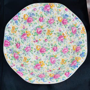 May include: A white ceramic bowl with a floral pattern. The bowl is decorated with pink, yellow, and blue flowers on a white background.