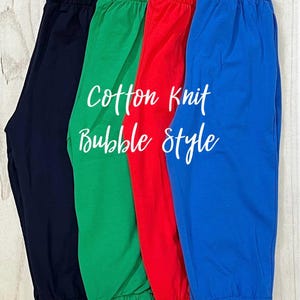 May include: Four pairs of cotton knit bubble style pants in navy, green, red, and blue. The pants have an elastic waistband and cuffs. The words "Cotton Knit Bubble Style" are written in white script.
