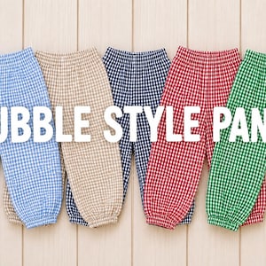 May include: Five pairs of bubble style pants in light blue, beige, navy blue, red, and green gingham patterns. Each pair features an elastic waistband and elasticized cuffs at the ankles. The text BUBBLE STYLE PANTS is centered over the items.