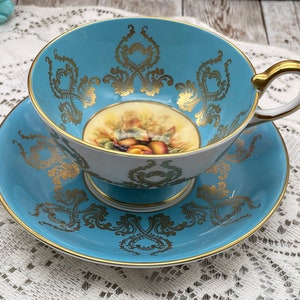 Aysnley turquoise, white and gold with fruit center footed tea cup and saucer set. Vintage bone china England