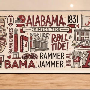 May include: A rectangular serving tray with two wooden handles featuring a cream background and maroon illustrations of Alabama Crimson Tide landmarks, including Gorgas Library, Bama Chimes, Big Al the elephant, and text reading Roll Tide.